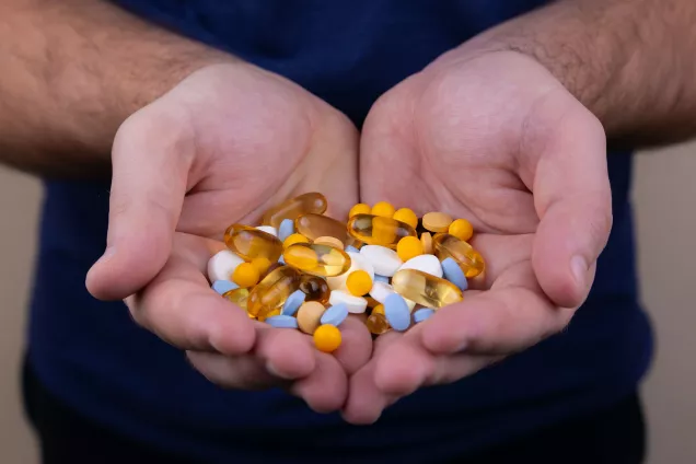 Människa som håller piller och läkemedel i sina händer. Foto.