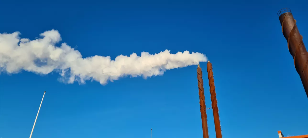White industrial smoke against clear blue sky. Photo.